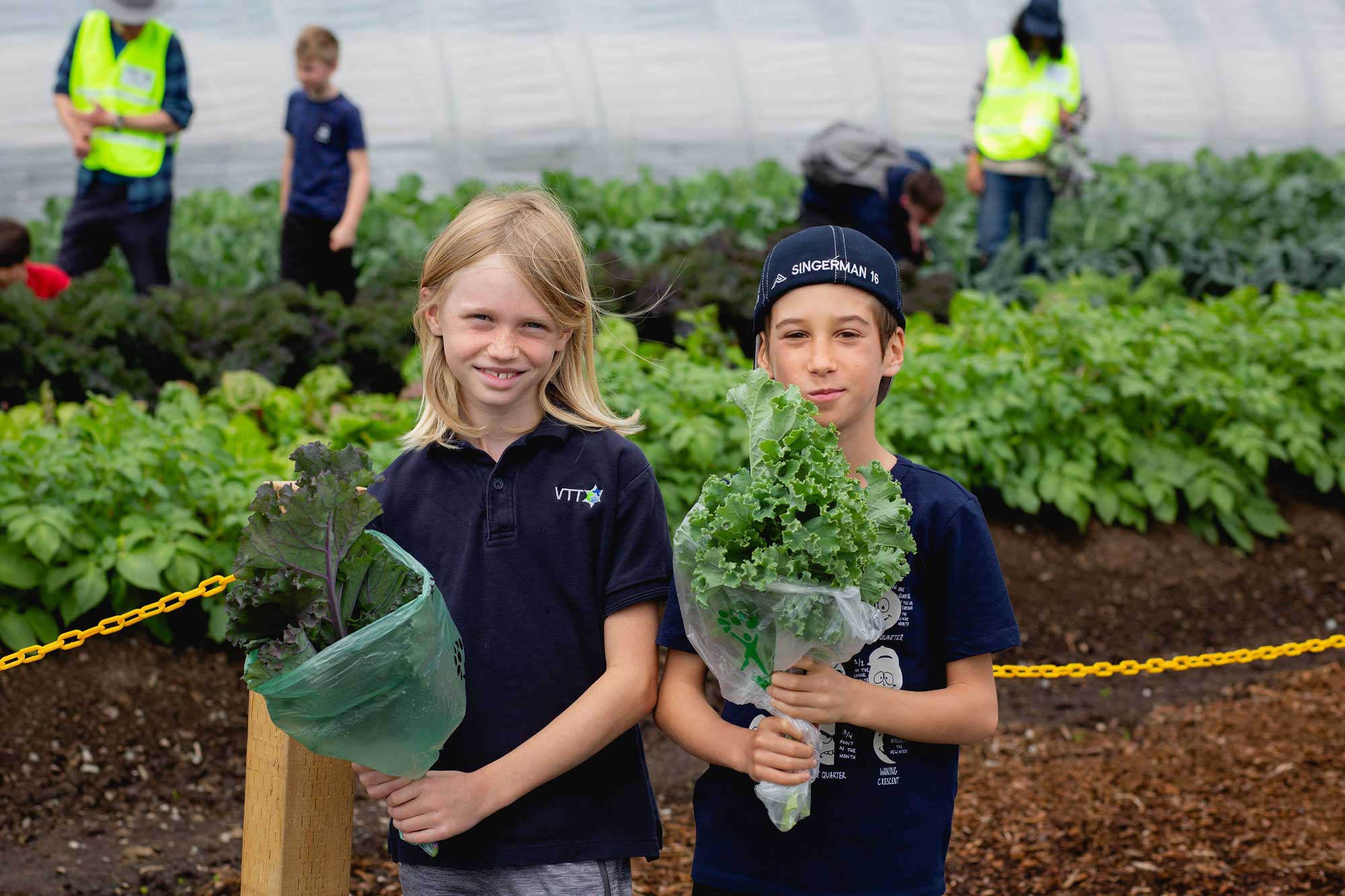 young kids holding kale in a greenhouse
